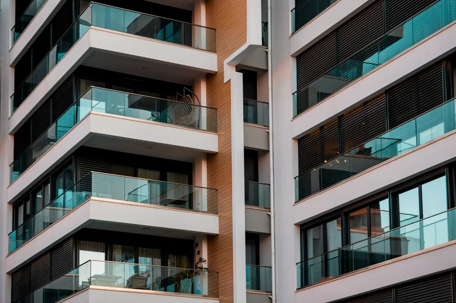 Edificio moderno de departamentos con balcones de vidrio (foto referencial)